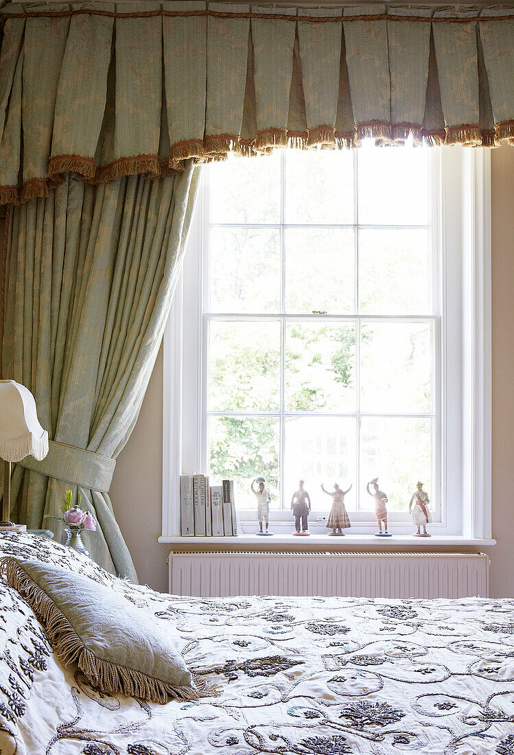 Figuren auf Fensterbank mit bestickter Bettdecke in traditionellem Landhaus Welsh Borders UK
