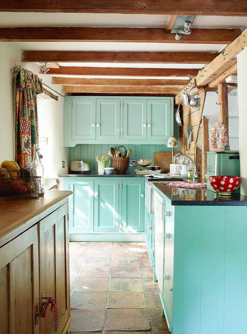 Balkenküche mit türkisfarbenen Einbauschränken in einem Cottage in Devonshire England