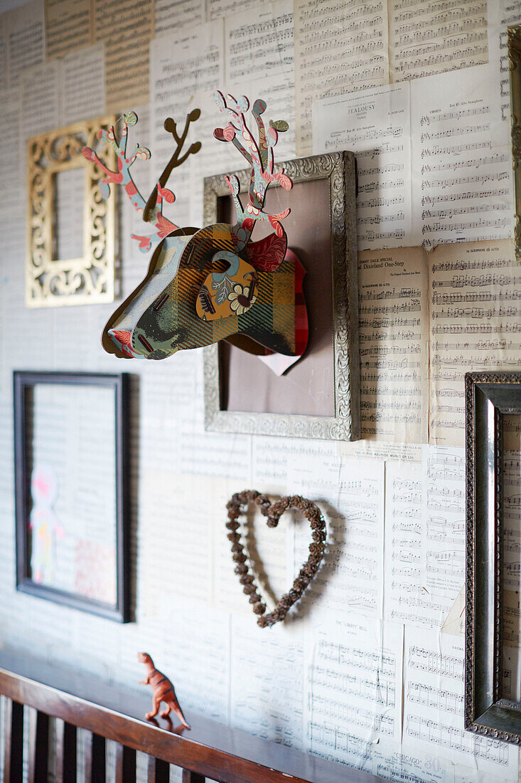 Wall-mounted deers head with empty picture frames with music scores in Kent home England UK