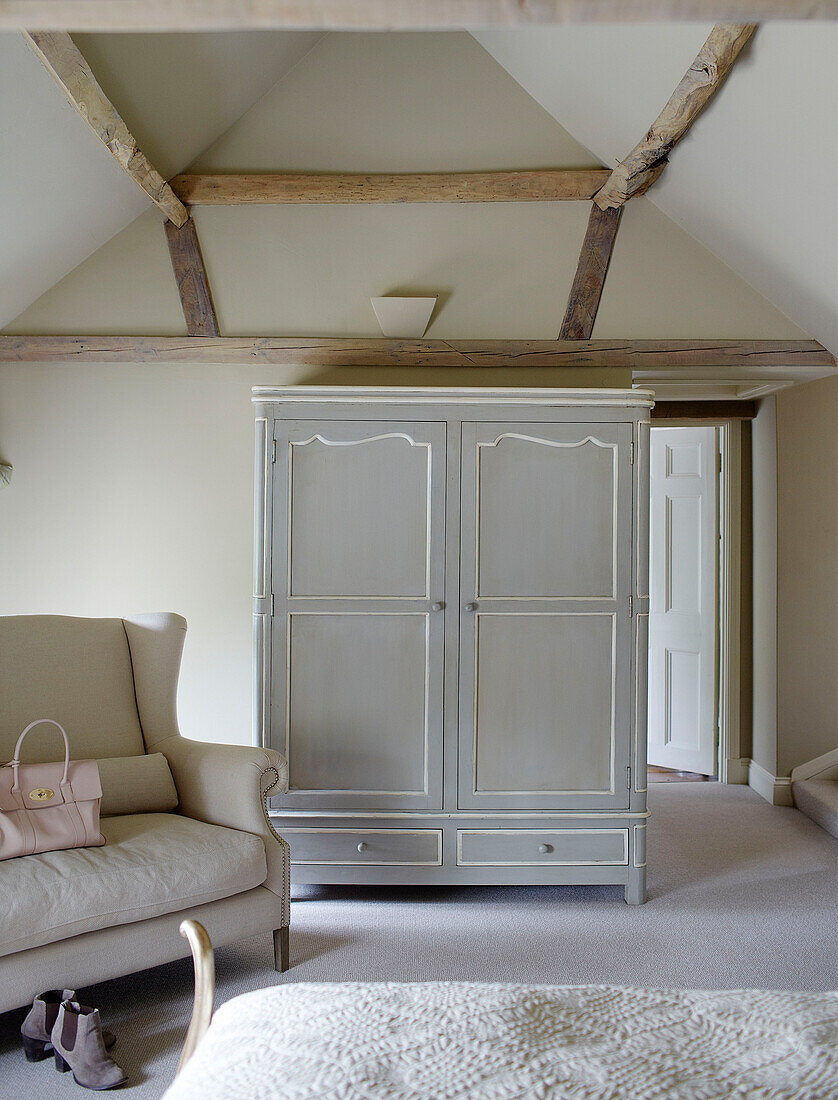 Light grey wardrobe and sofa in beamed Buckinghamshire bedroom UK