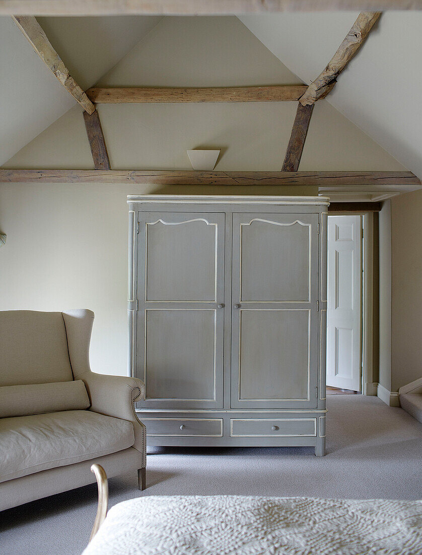 Hellgrauer Kleiderschrank und Sofa in einem Schlafzimmer mit Balken in Buckinghamshire UK