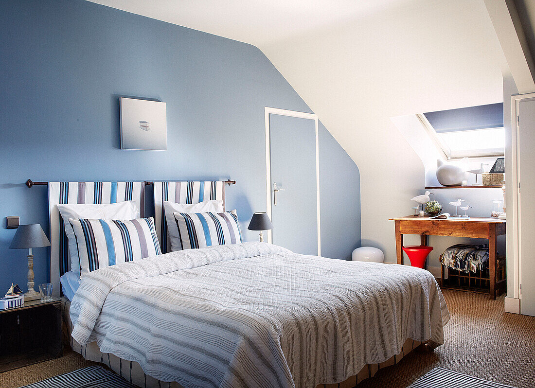 Gestreifte Kissen mit passendem Kopfteil im hellblauen Schlafzimmer eines bretonischen Gästehauses in Frankreich