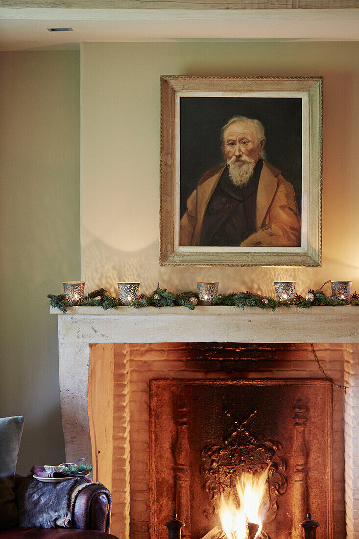 Framed portrait above lit fire in Oxfordshire home England UK