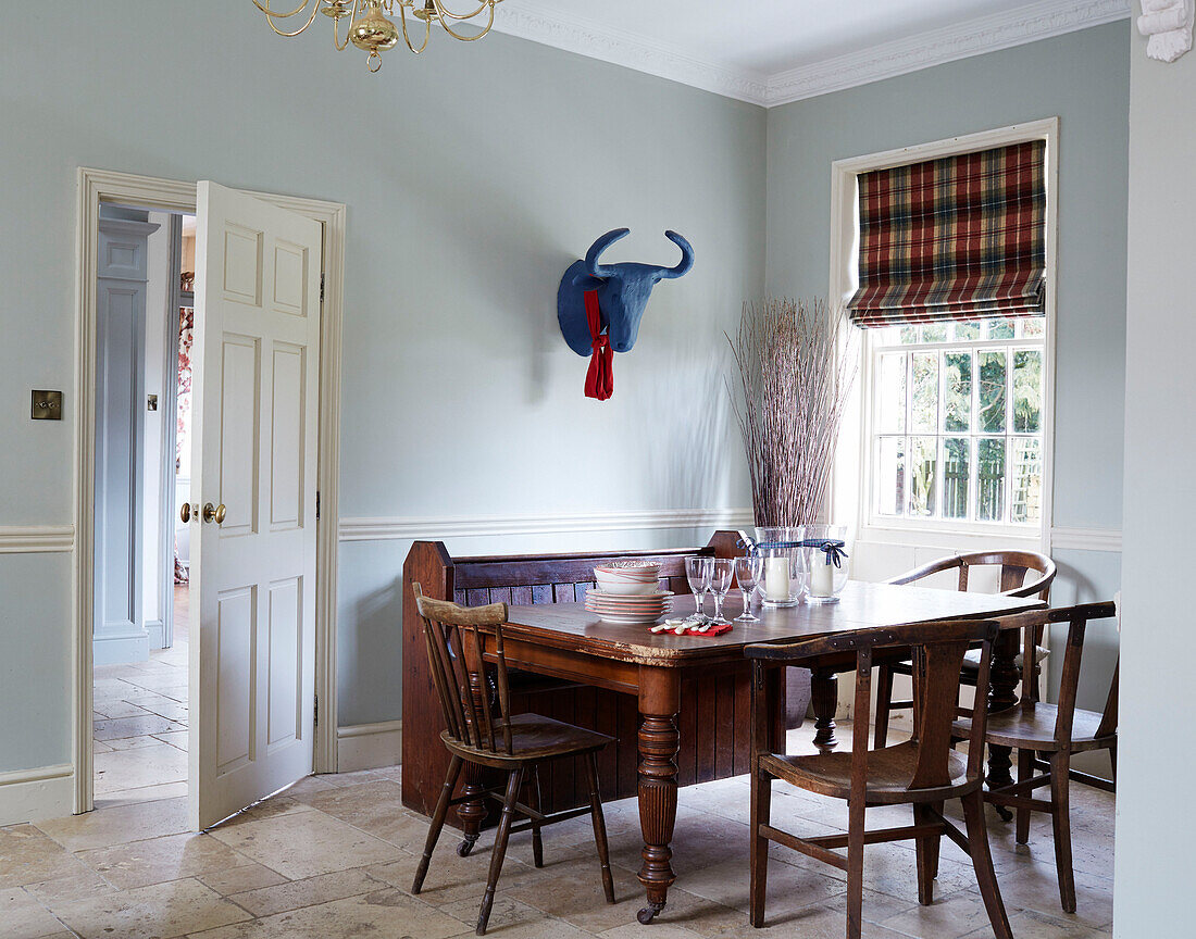 Hölzerner Esstisch und Stuhl mit blauem Tierkopf am Fenster in einem Haus in der Grafschaft Durham, England, UK