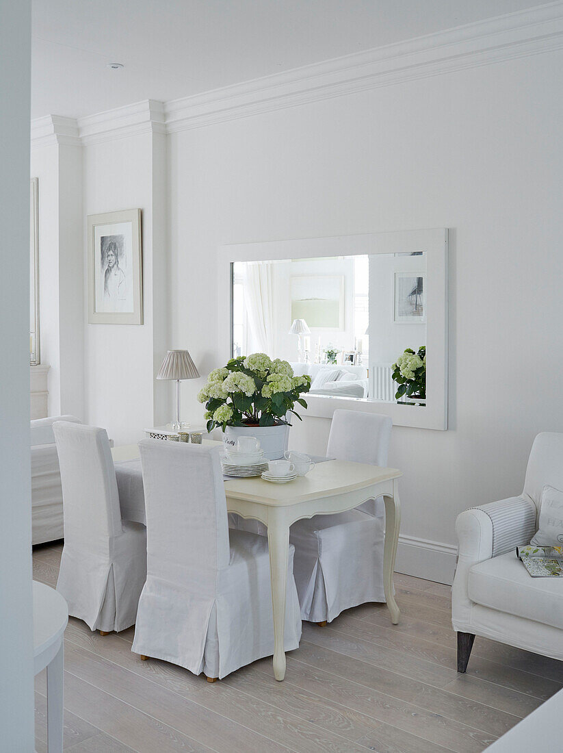 Weiße Bezüge auf Esszimmerstühlen an einem Tisch mit Spiegel in einem Stadthaus in York England UK