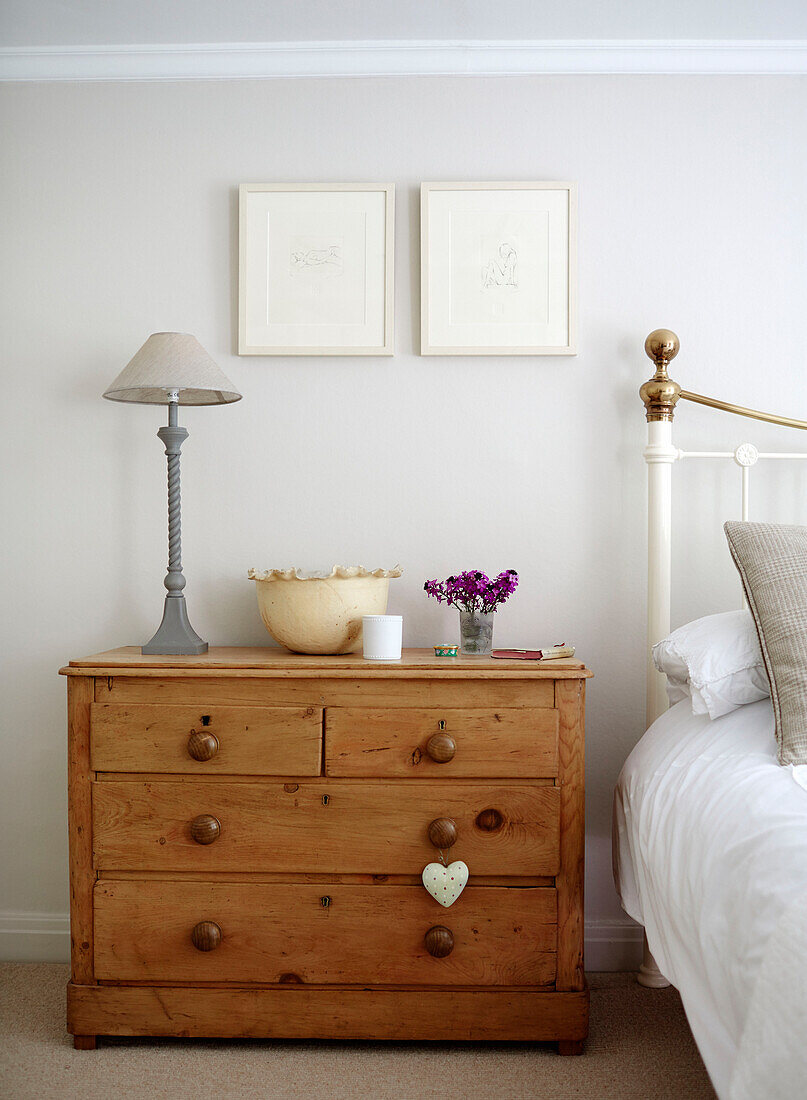 Grey lamp on wooden chest of drawers at bedside in Northumbrian home England UK