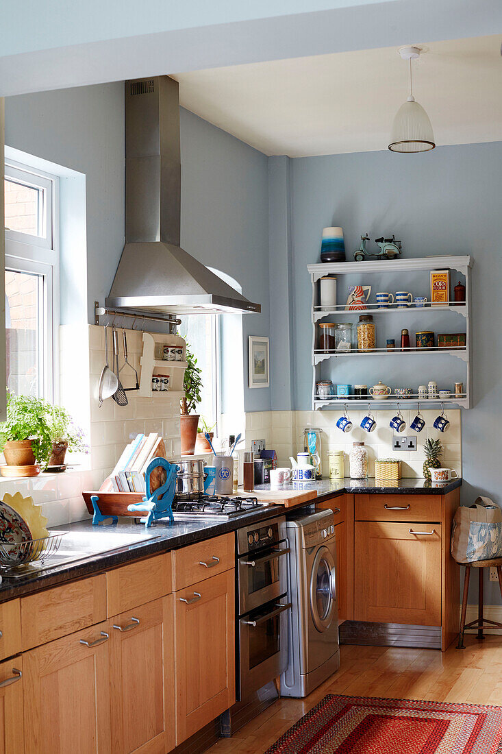 Dunstabzugshaube aus Edelstahl über der Küchenarbeitsplatte mit wandmontierten Regalen in einem Haus in Birmingham, England, UK