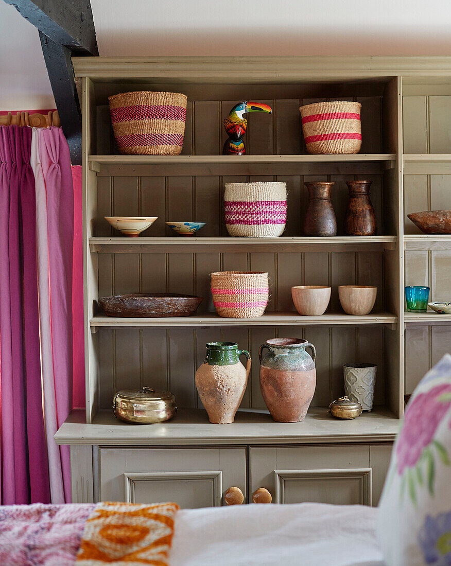Earthenware and baskets on shelf unit in bedroom of 18th century Northumbrian mill house, UK