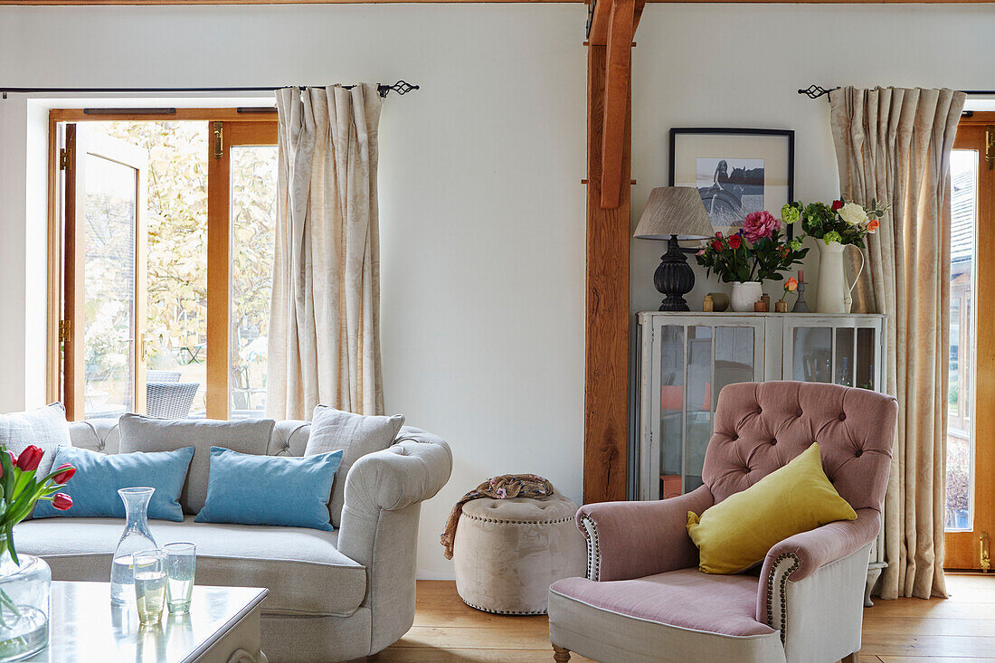 Pink buttoned armchair with sofa and open garden door in Kent home, England, UK