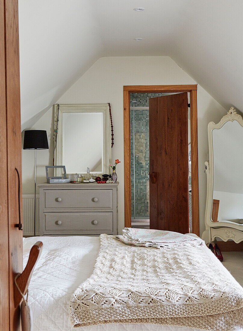 Häkeldecke auf einem Doppelbett mit Holztür zum Bad in einem Haus in Kent, Nordostengland, UK