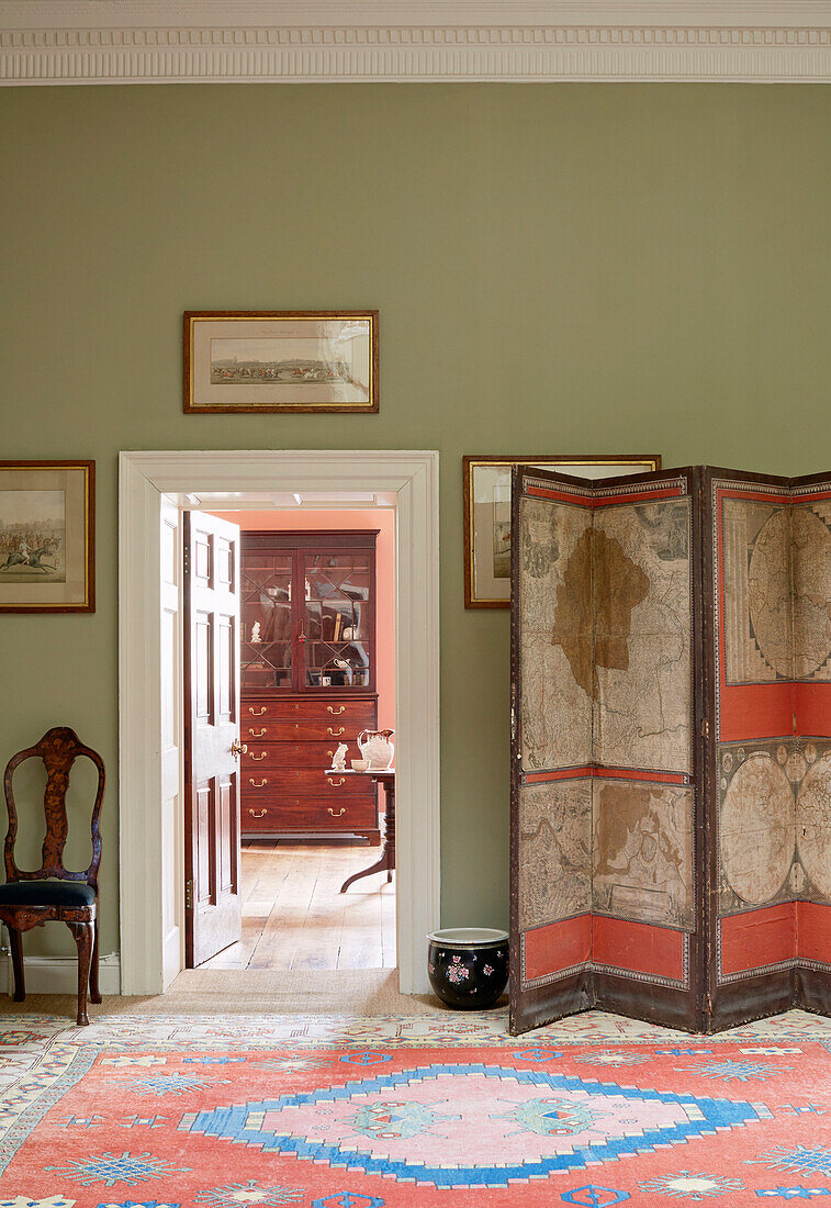 Antiker Paravent und gemusterter Teppich mit Blick durch eine Tür in Capheaton Hall in Northumberland, UK