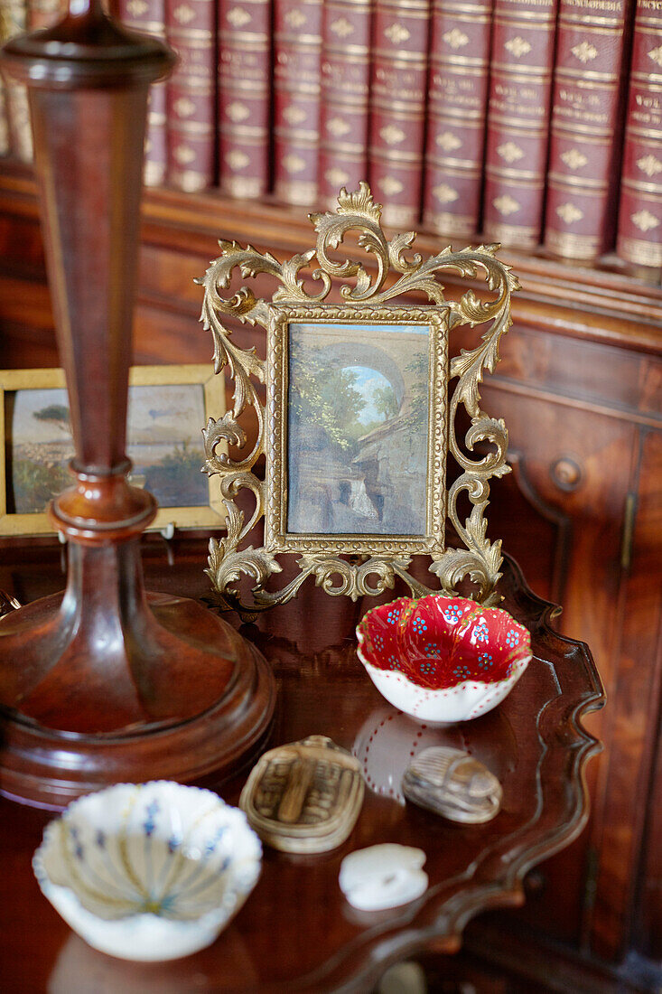Gilt framed artwork and ornaments on polished side table in Capheaton Hall, Northumberland, UK