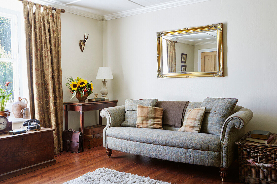 Great sofa below gilt framed mirror in Northumberland cottage, Tyne and Wear, England, UK