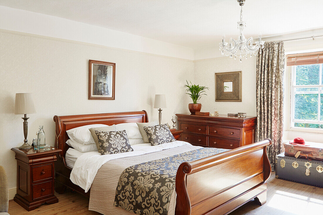 Polished wooden sleigh bed with foliate fabric coverings in Northumberland cottage, Tyne and Wear, England, UK