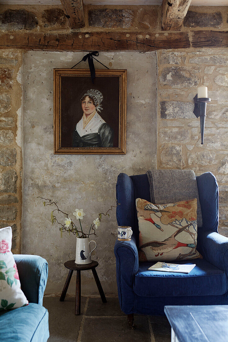 Blue wingback armchair below framed oil painting in Grade II listed Tudor bastle Northumberland UK