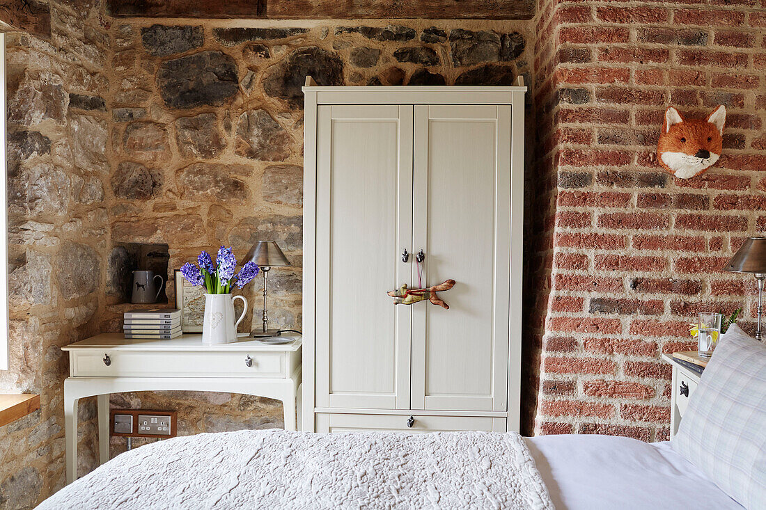 White wardrobe and table with exposed brick and stone in Grade II listed Tudor bastle Northumberland UK