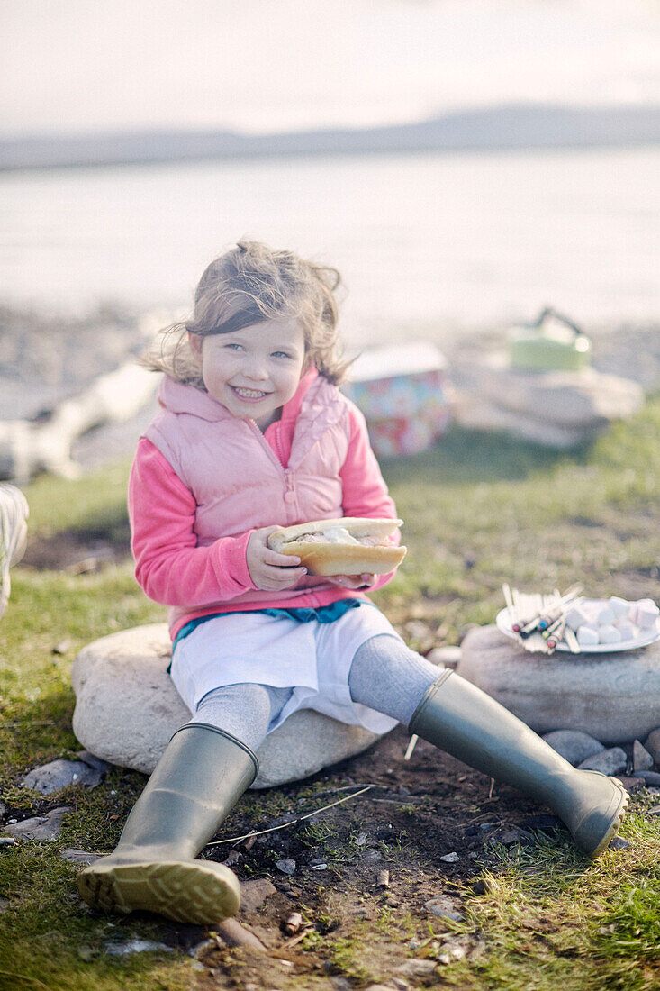 Girls sits on rock at beach eating salmon baguette in County Sligo Connacht Ireland