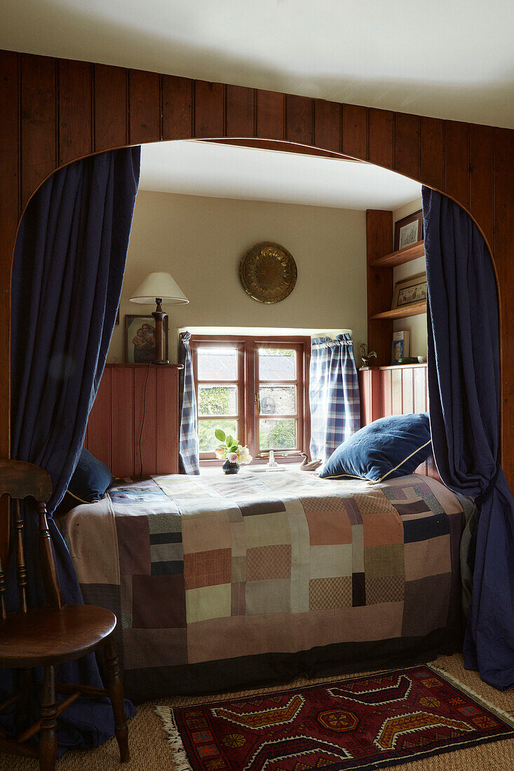 Doppelbett mit Patchwork-Steppdecke am Fenster eines Bauernhauses in Herefordshire, UK