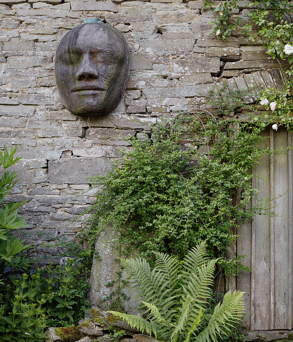 Geschnitztes Gesicht auf freiliegendem Stein am Tor in einem Garten in Herefordshire, UK