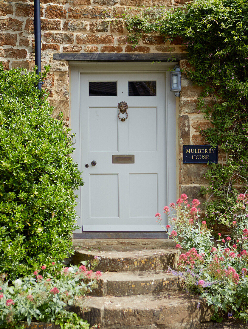 Eingangstür mit Stufen aus Stein eines Landhauses in Oxfordshire, England, UK