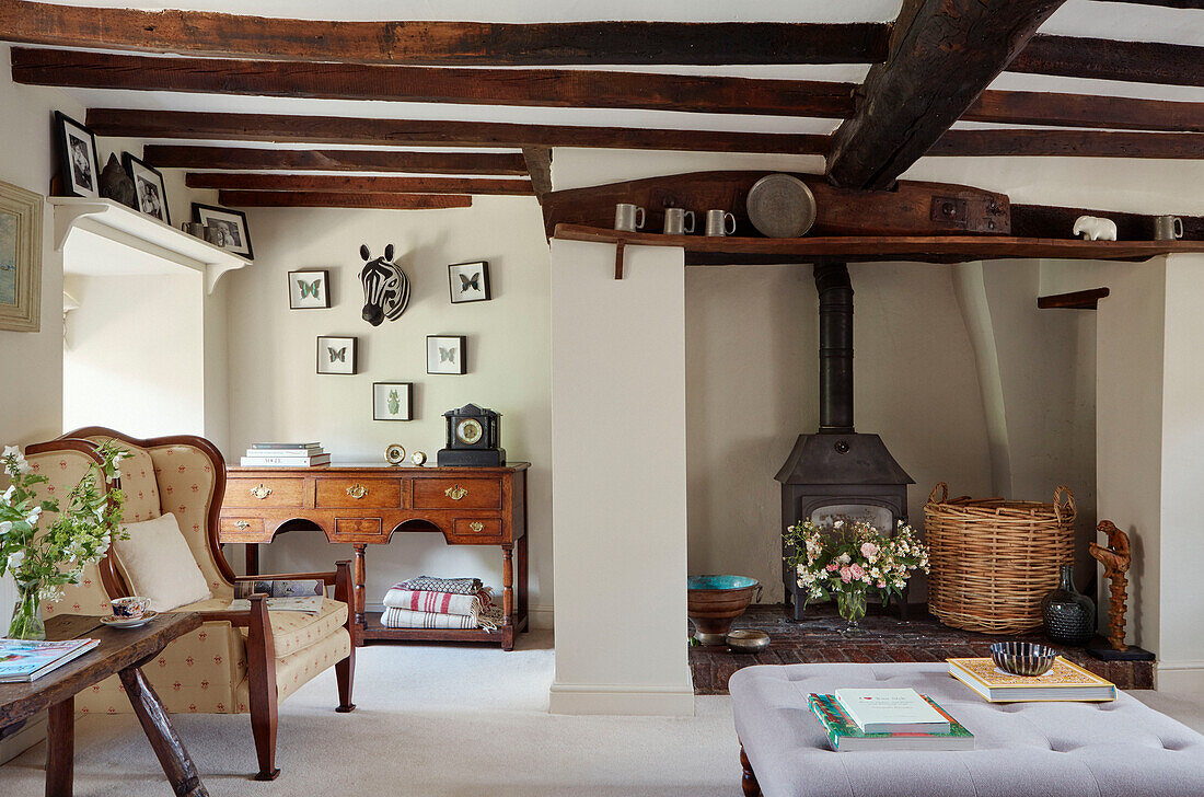 Woodburner and sideboard under beamed ceiling in Oxfordshire cottage, England, UK
