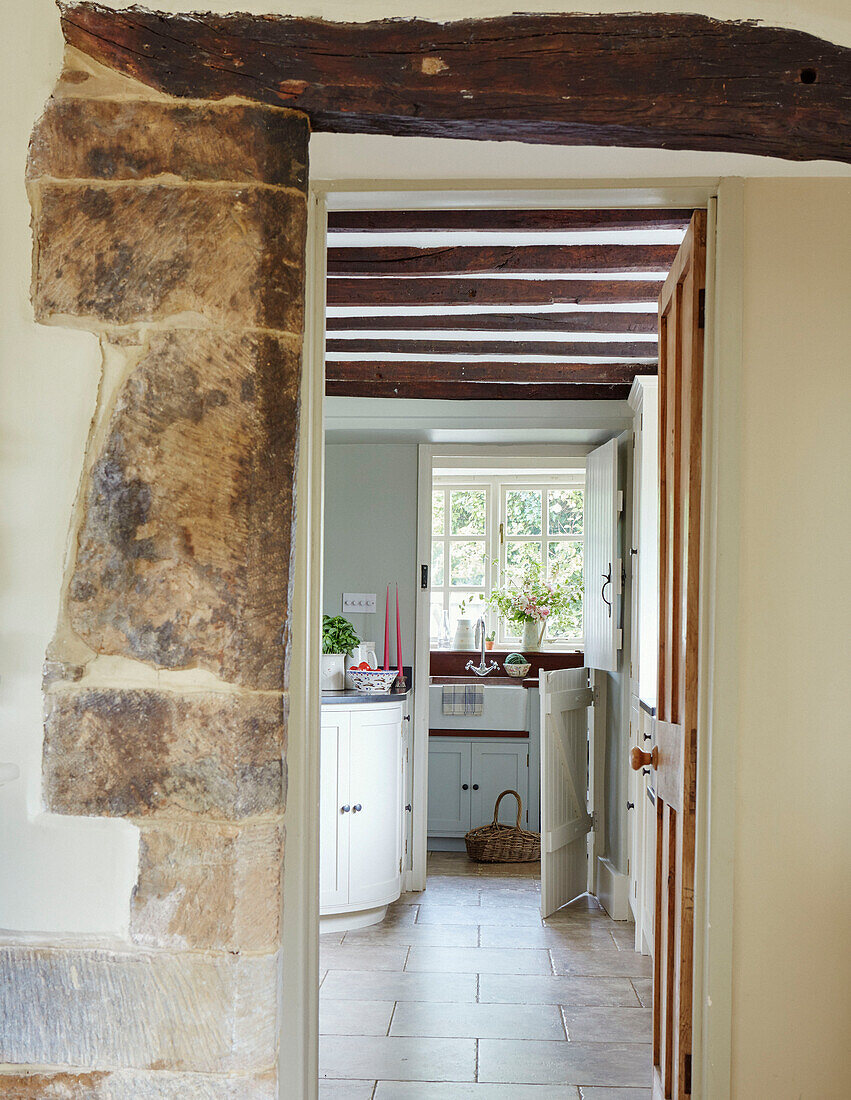 Freigelegtes Steinmauerdetail mit Blick durch die Tür zur Balkenküche in einem Haus in Oxfordshire, UK