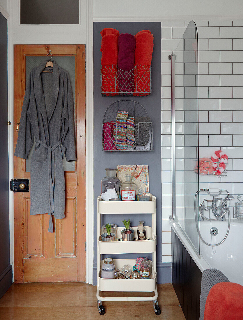 Grey dressing gown with orange towels and toiletries on shelf in Chippenham bathroom, Wiltshire, UK