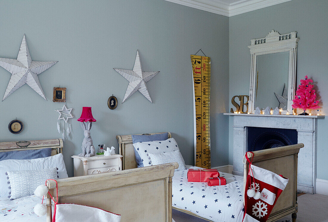 Lit tealights on fireplace in child's twin room with stars above beds East Grinstead home, West Sussex, UK