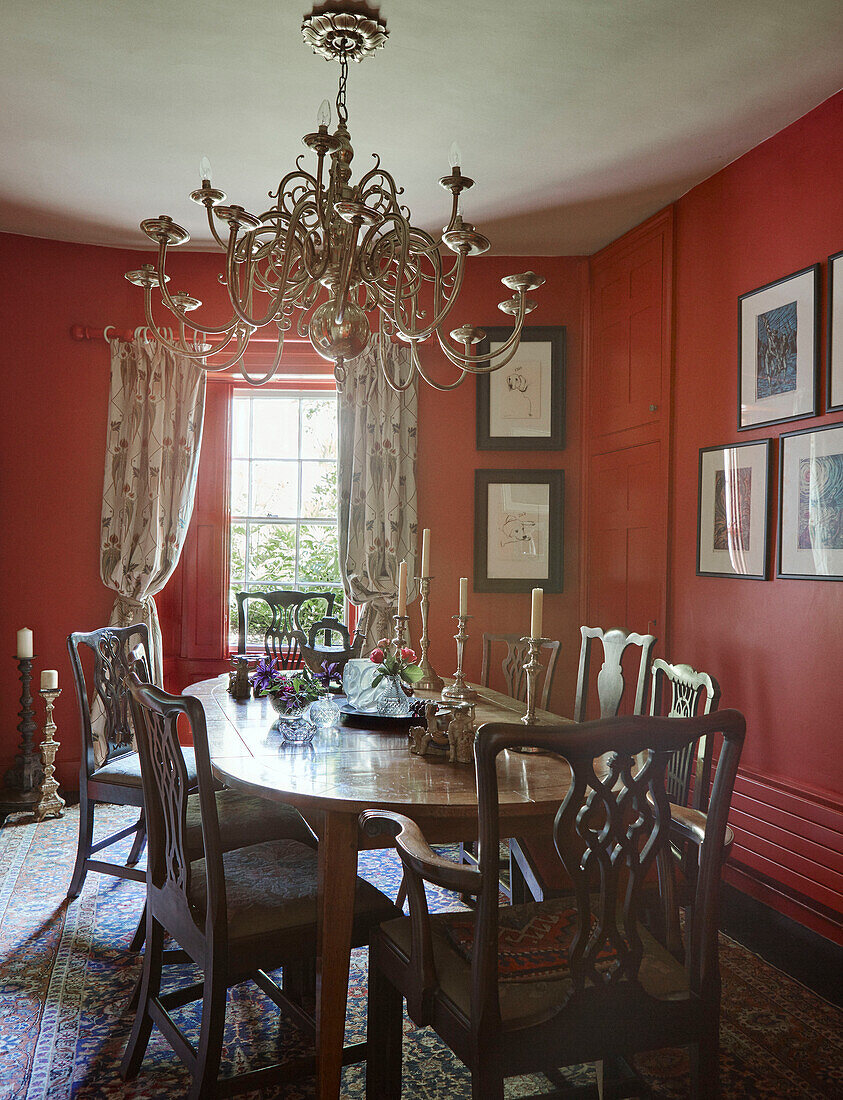 Wooden table and chairs with metal chandelier in red 19th century Georgian dining room in Talgarth, Mid Wales, UK