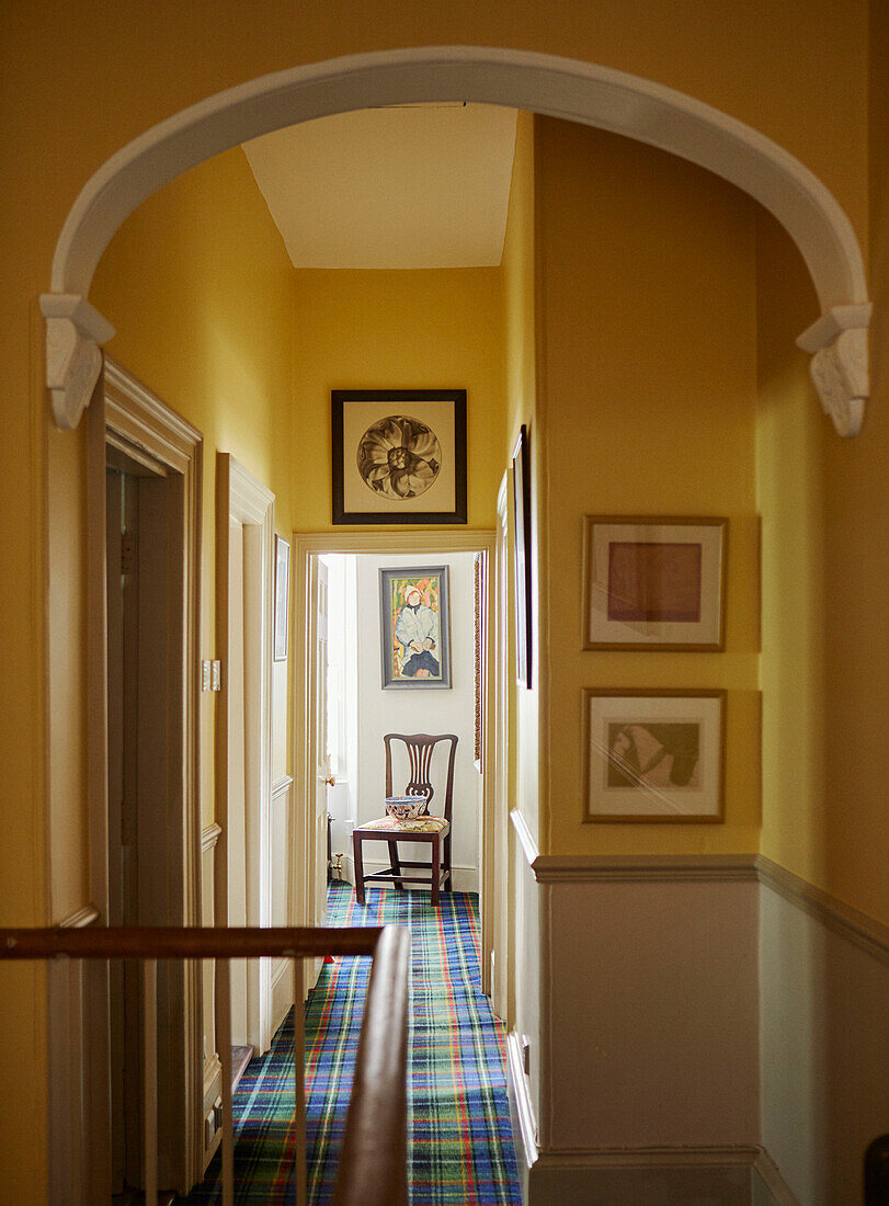 Yellow hall with archway and tartan carpet in 19th century Georgian townhouse in Talgarth, Mid Wales, UK