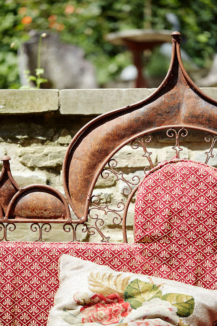 Ironwork seat with Victorian fabric in garden of Georgian home in Talgarth, Mid Wales, UK