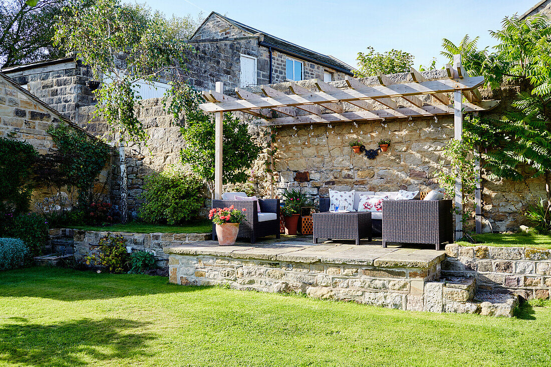 Garden furniture on raised terrace with pergola in garden of Yorkshire home, England, UK