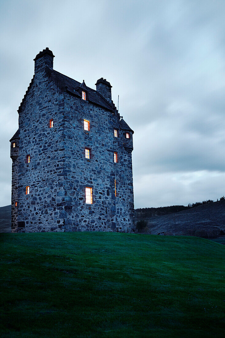 Beleuchtete Fenster in einem abgelegenen schottischen Schloss, UK