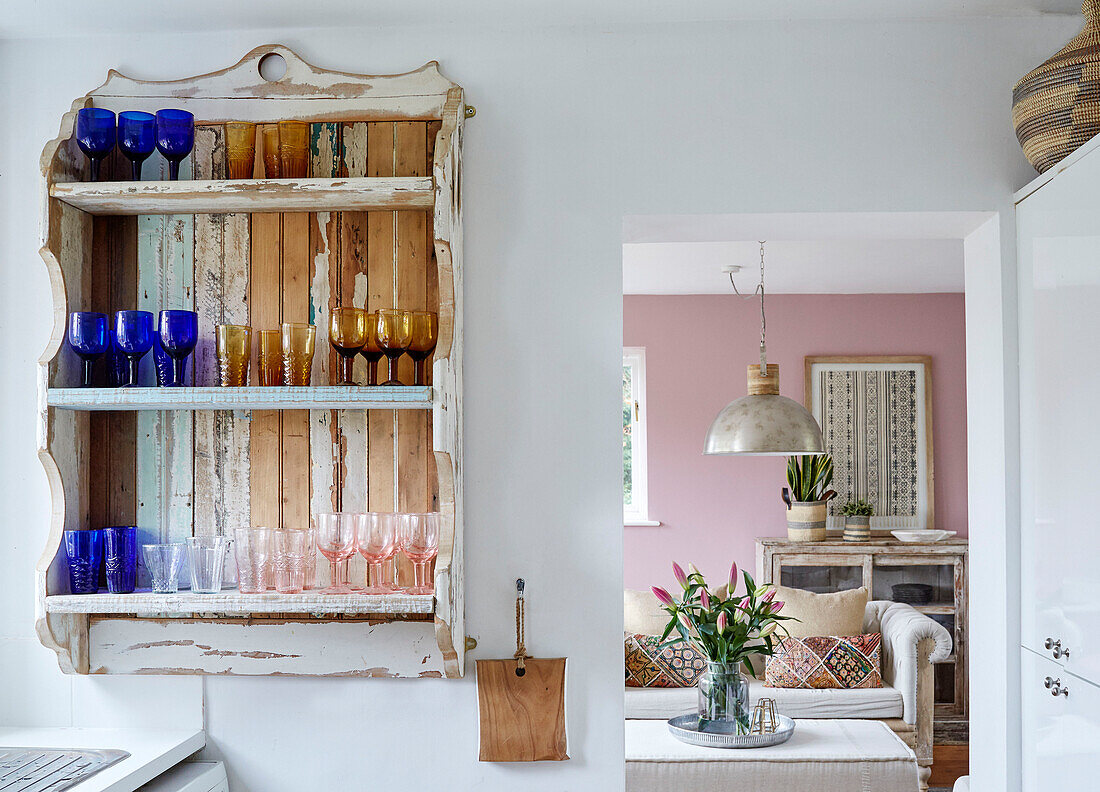 Blick durch Türöffnung auf Sammlung von Glaswaren auf einem Wandregal mit Lilien in einem Haus in Tunbridge Wells, Kent, UK