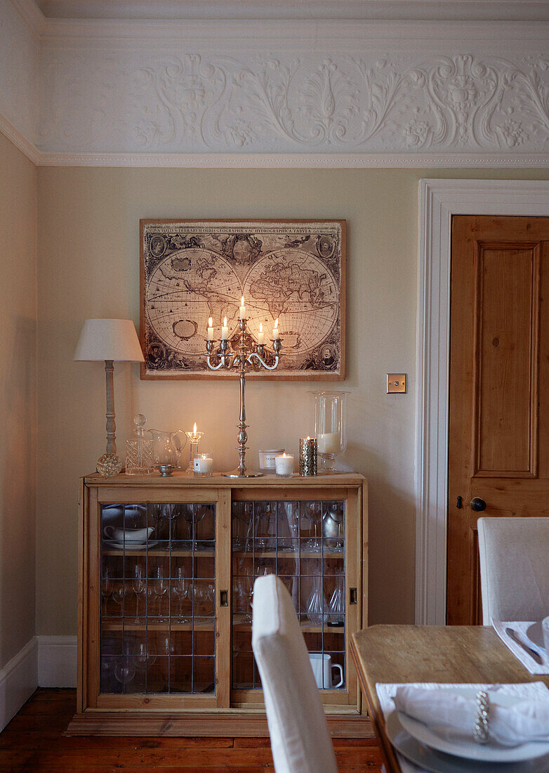 Wandkarte und brennende Kerzen über einer Glasvitrine im Esszimmer eines britischen Hauses