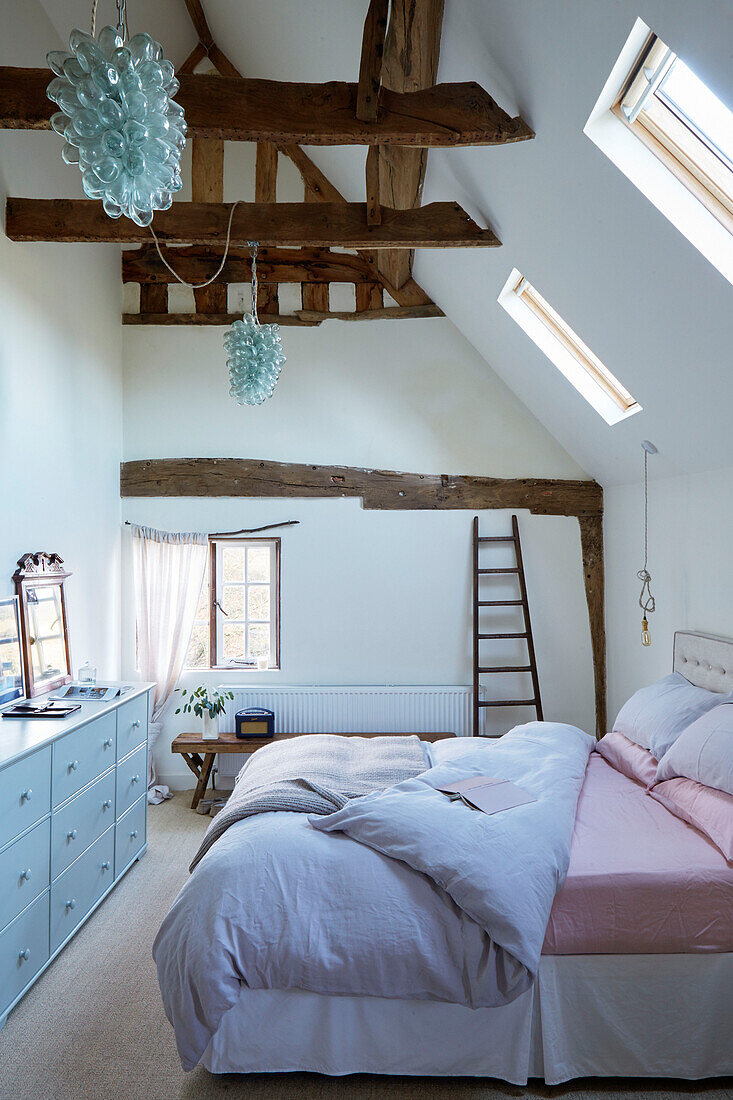 Coloured glass lights above double bed in Warwickshire farmhouse attic conversion, England, UK