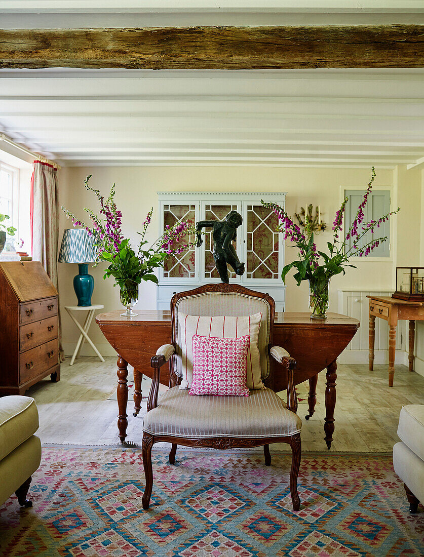 Cut flowers and upcycled armchair in Sandford St Martin cottage, Oxfordshire, UK