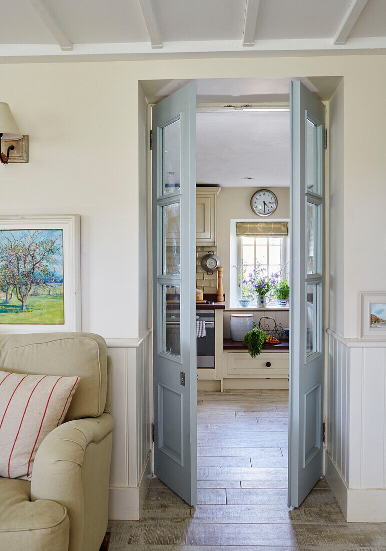 Blick durch Flügeltüren in die Küche von einem Cottage in Sandford St Martin, Oxfordshire, UK