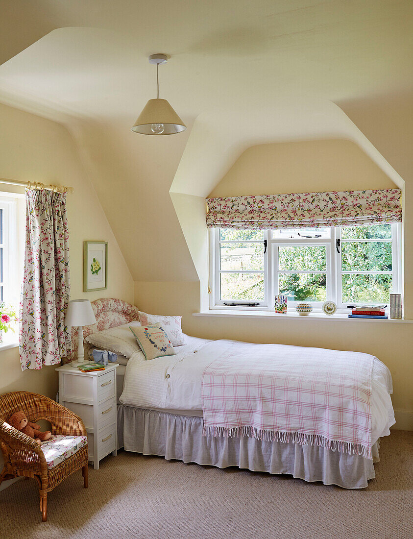 Einzelbett und Stuhl im Mädchenzimmer mit geblümten Vorhängen und Jalousien in einem Cottage in Sandford St Martin, Oxfordshire, UK