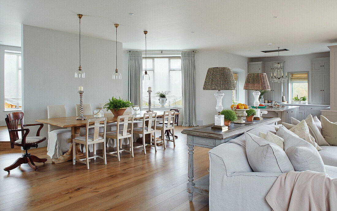 Table and chairs with pair of lamps on console in open plan Woodstock home, Oxfordshire, UK