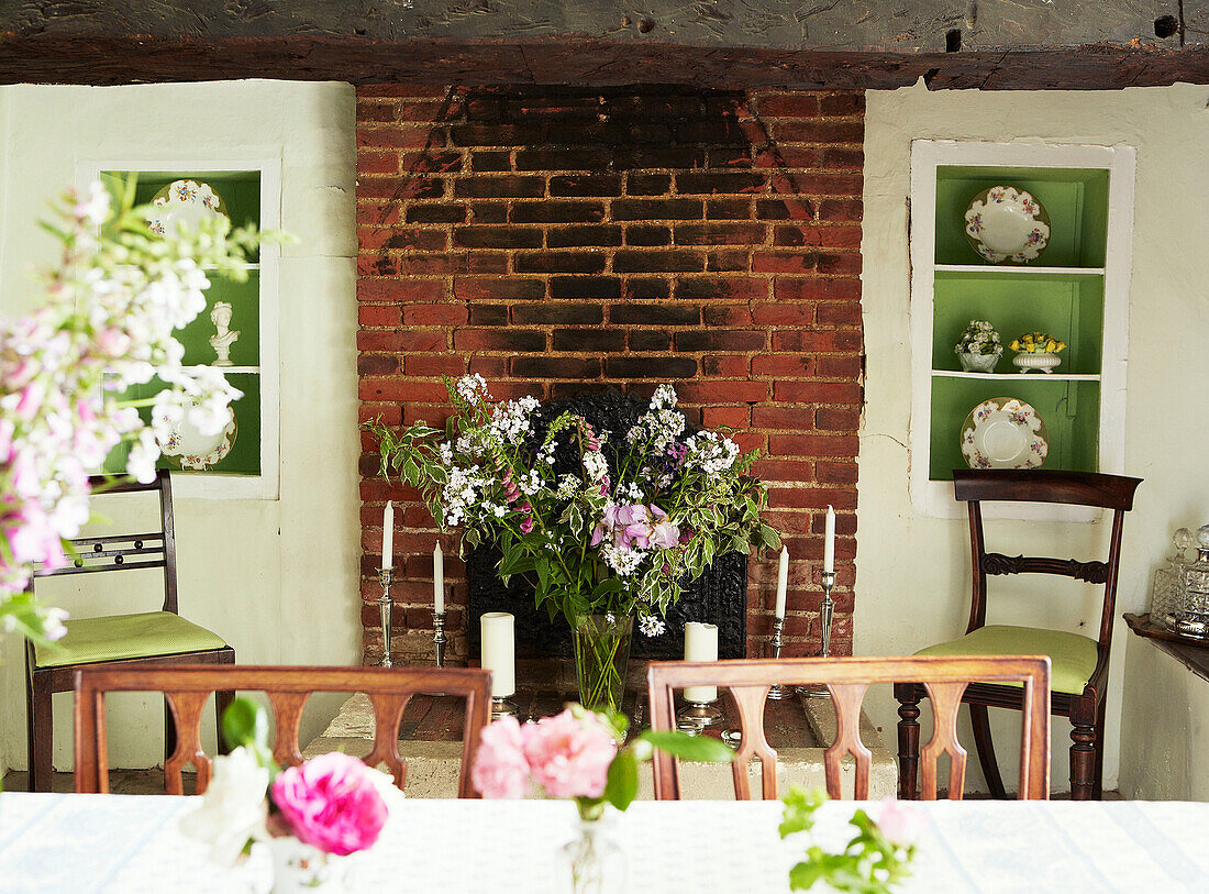 Cut flowers in exposed brick fireplace with recessed shelving Syresham home, Northamptonshire, UK
