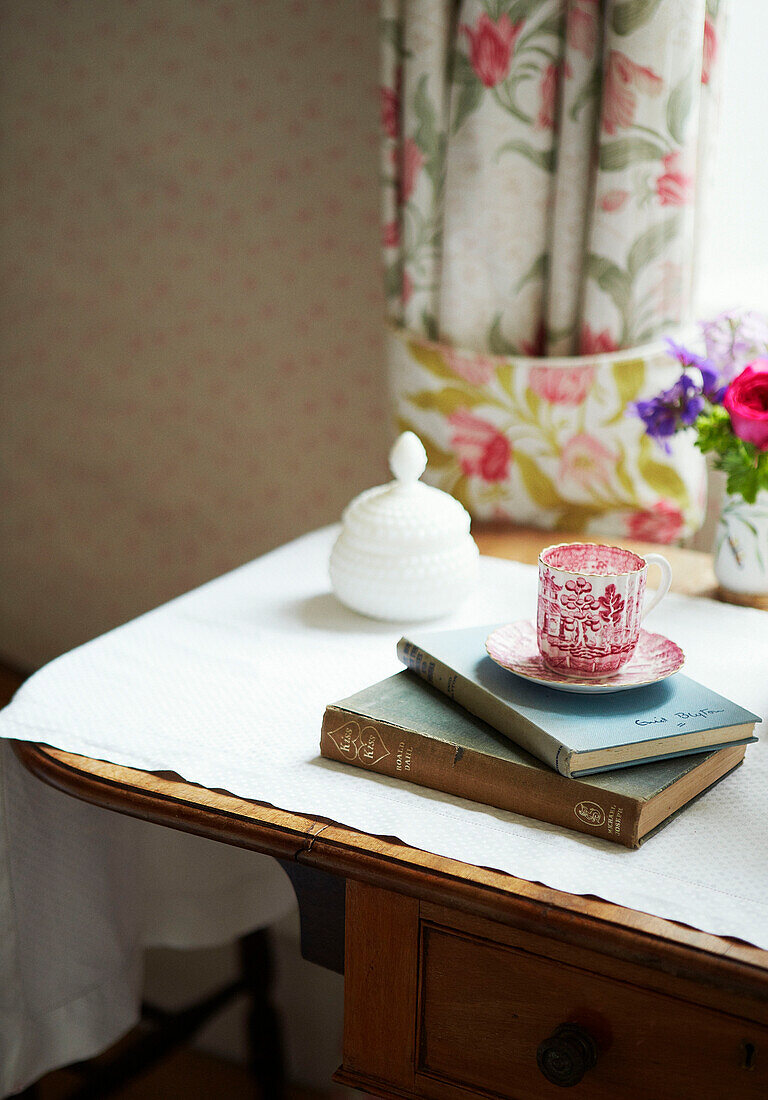 Vintage-Tasse und -Untertasse mit gebundenen Büchern auf dem Schminktisch in einem Haus in Syresham, Northamptonshire, UK