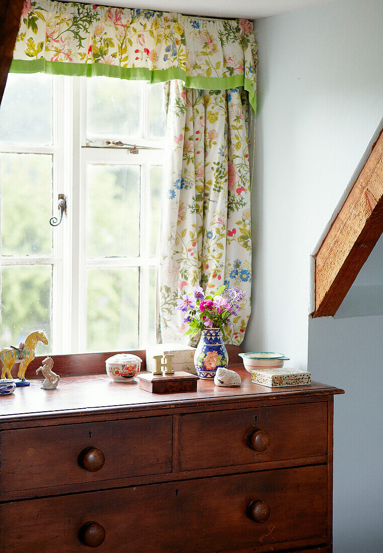 Schmuckstücke auf Holzkommode am Fenster mit geblümten Vorhängen in einem Haus in Syresham, Northamptonshire England, UK