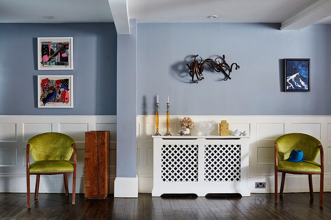 Paar Samtpolsterstühle mit Heizkörperabdeckung in einem hellblauen Zimmer in einem Haus in Deddington, Oxfordshire, England