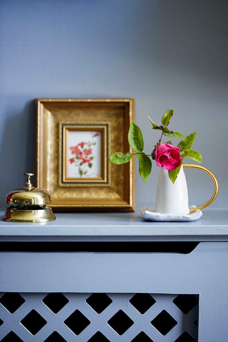 Einstämmige Rose und Dienstglocke mit gerahmtem Druck auf einem Regal in einem Haus in Deddington, Oxfordshire, UK