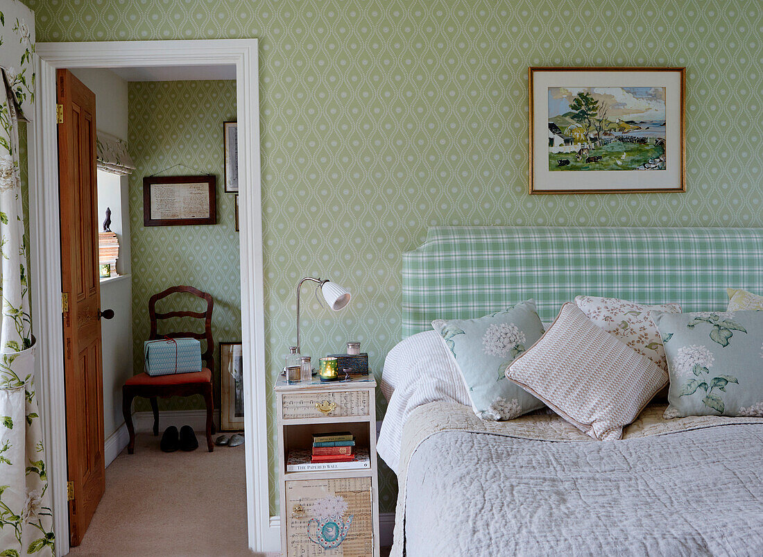 Kontrastierende Tapeten und Stoffmuster im Schlafzimmer eines Bauernhauses in Northumberland, UK