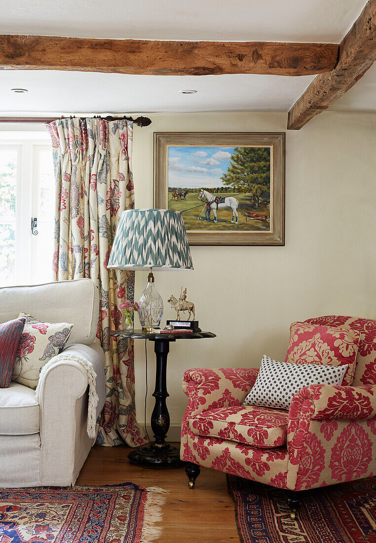 Kontrastierende Stoffe auf Sessel und Vorhängen in einem Landhaus in Berkshire, England, UK