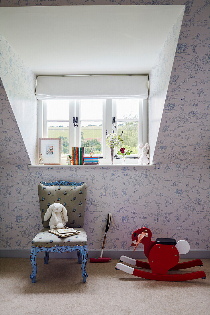 Spielzeug mit Stuhl unter dem Fenster im Kinderzimmer eines Landhauses in Berkshire, England, UK