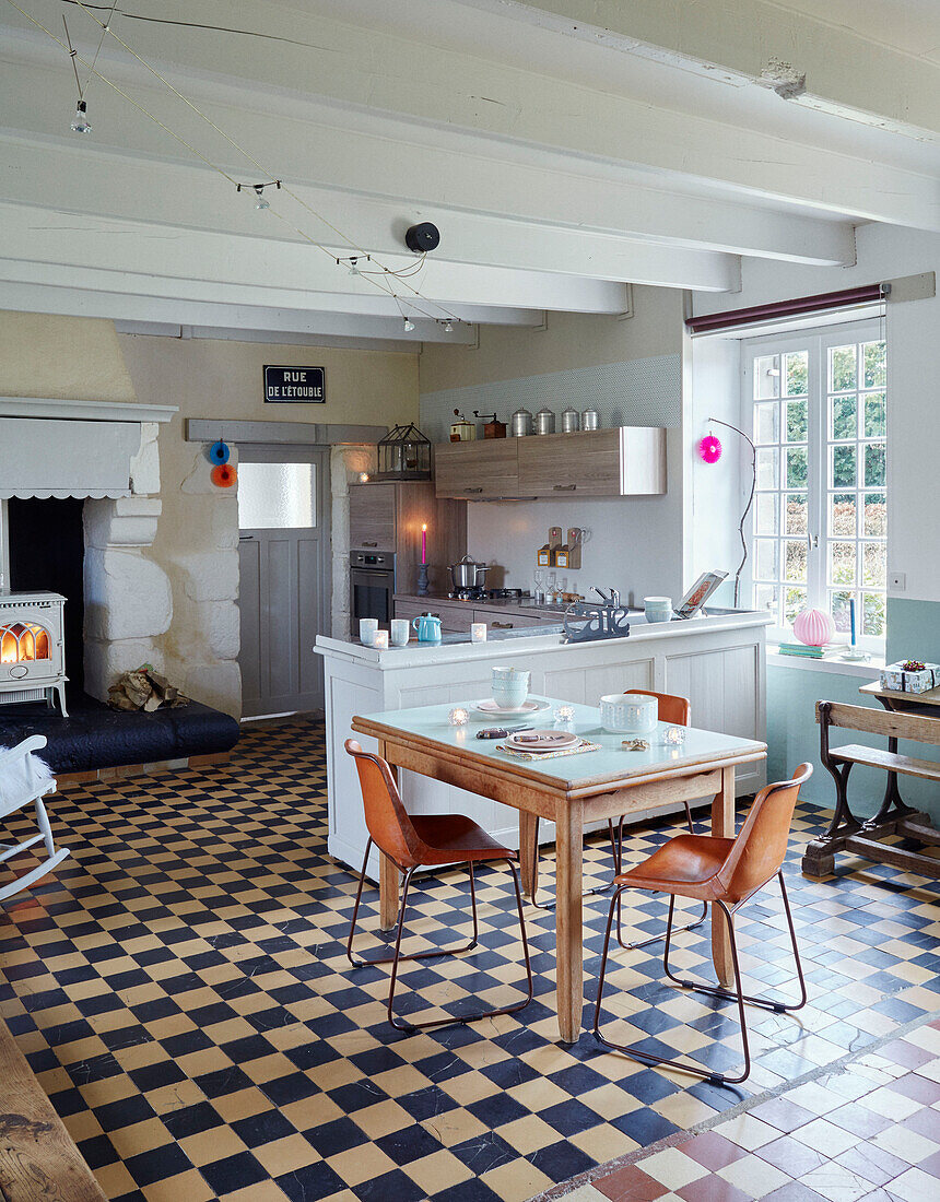 Retro style chairs at table in open plan kitchen of Brittany cottage, France