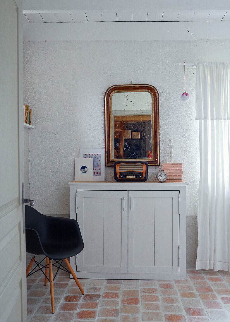 Mirror and radio on sideboard with DSW chair in Brittany cottage, France